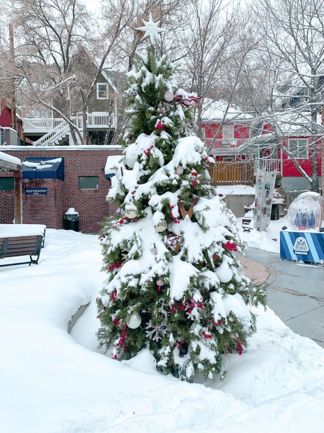 happy real Christmas tree decorated in downtown Park City, Utah with snow all around and colorful ornaments